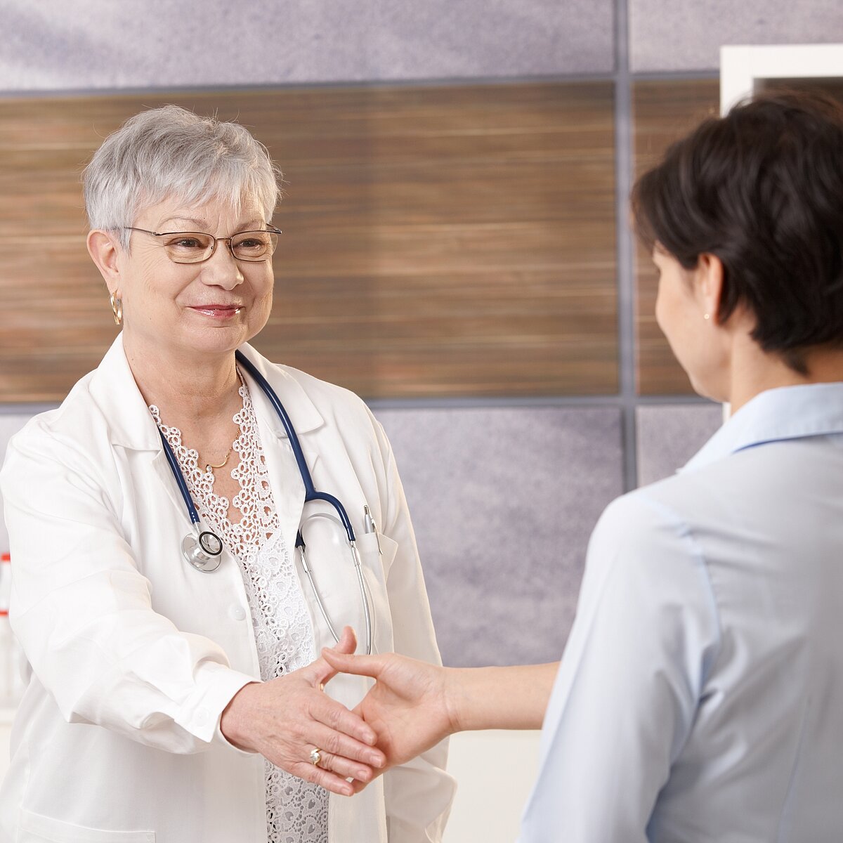 Erfahrene Ärztin begrüßt eine Patientin.